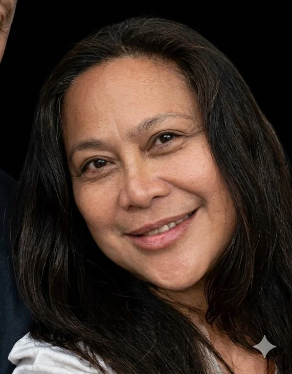 A close-up portrait of a smiling woman with long dark hair and light skin, against a black background.
