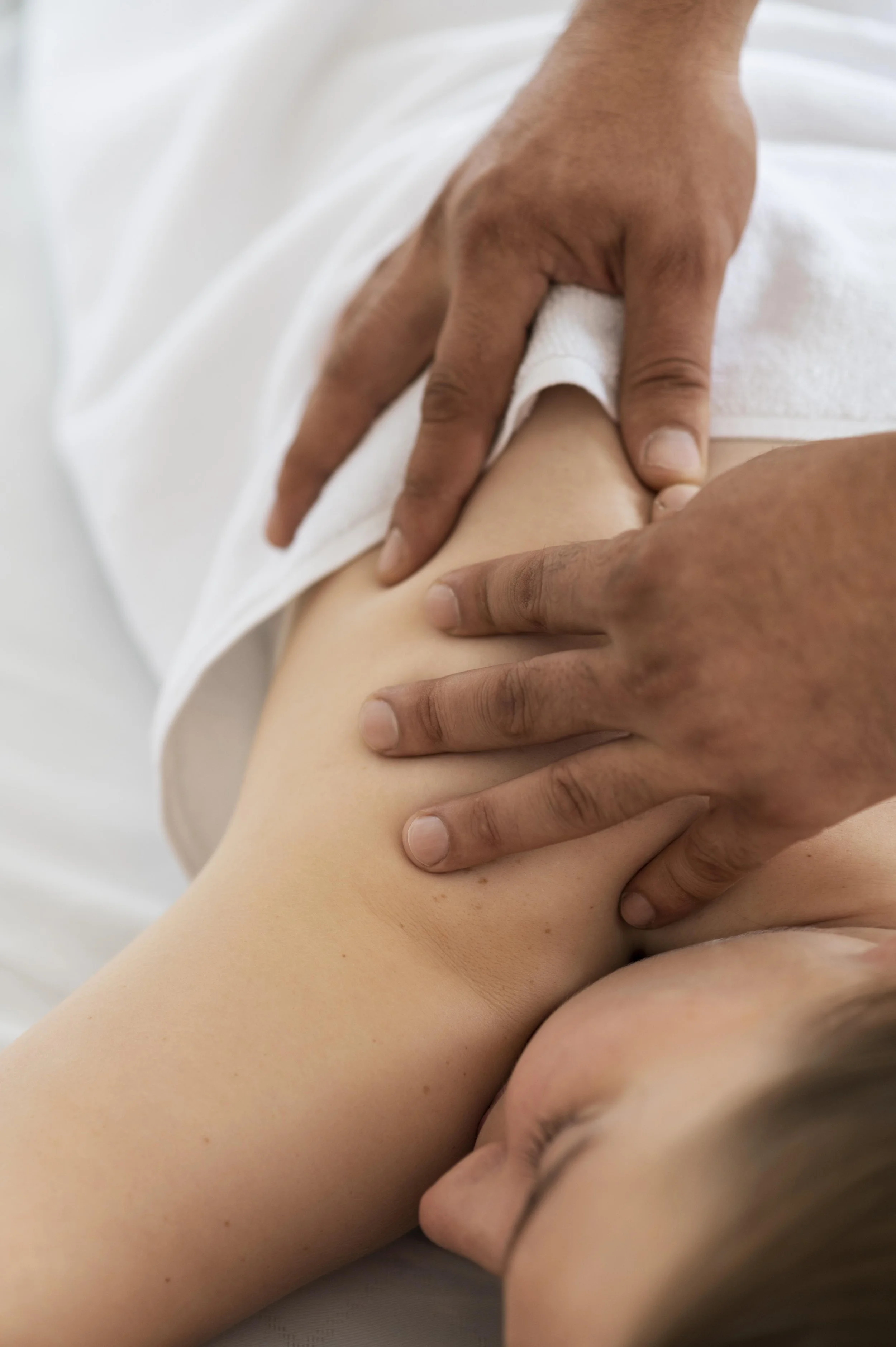 Close-up of a massage therapist's hands performing a massage on a person's arm.