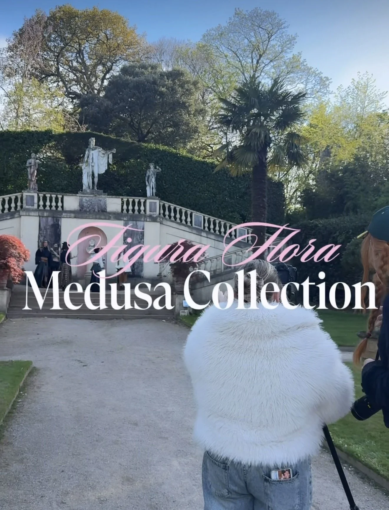 A person wearing a fluffy white animal costume, possibly a bear or a dog, standing in a park with trees and statues in the background. There's a person taking a photo on the right, and the text overlay reads 'Ligura Flora Medusa Collection'.