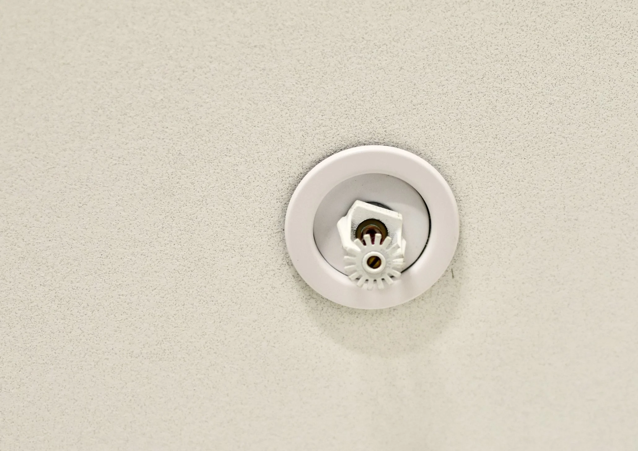 Ceiling light fixture with a white trim and adjustable fluorescent bulb, mounted on a textured ceiling.