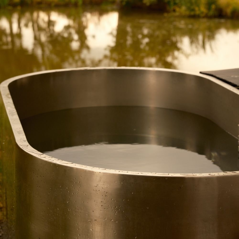 Stainless steel cold plunge bath besides a lake