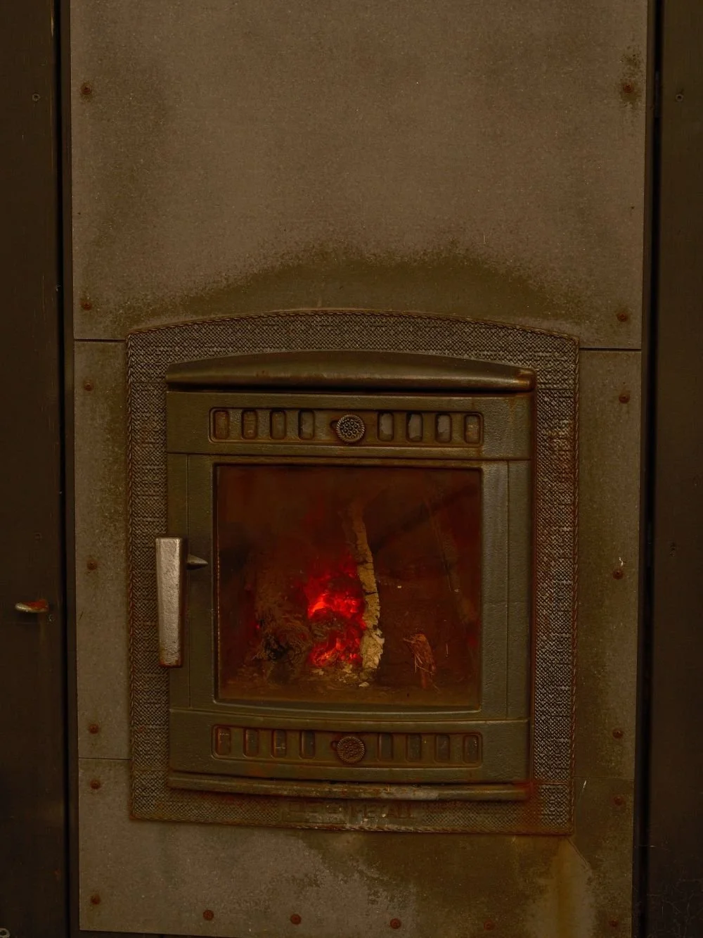 Wood burning sauna stove with glowing embers inside