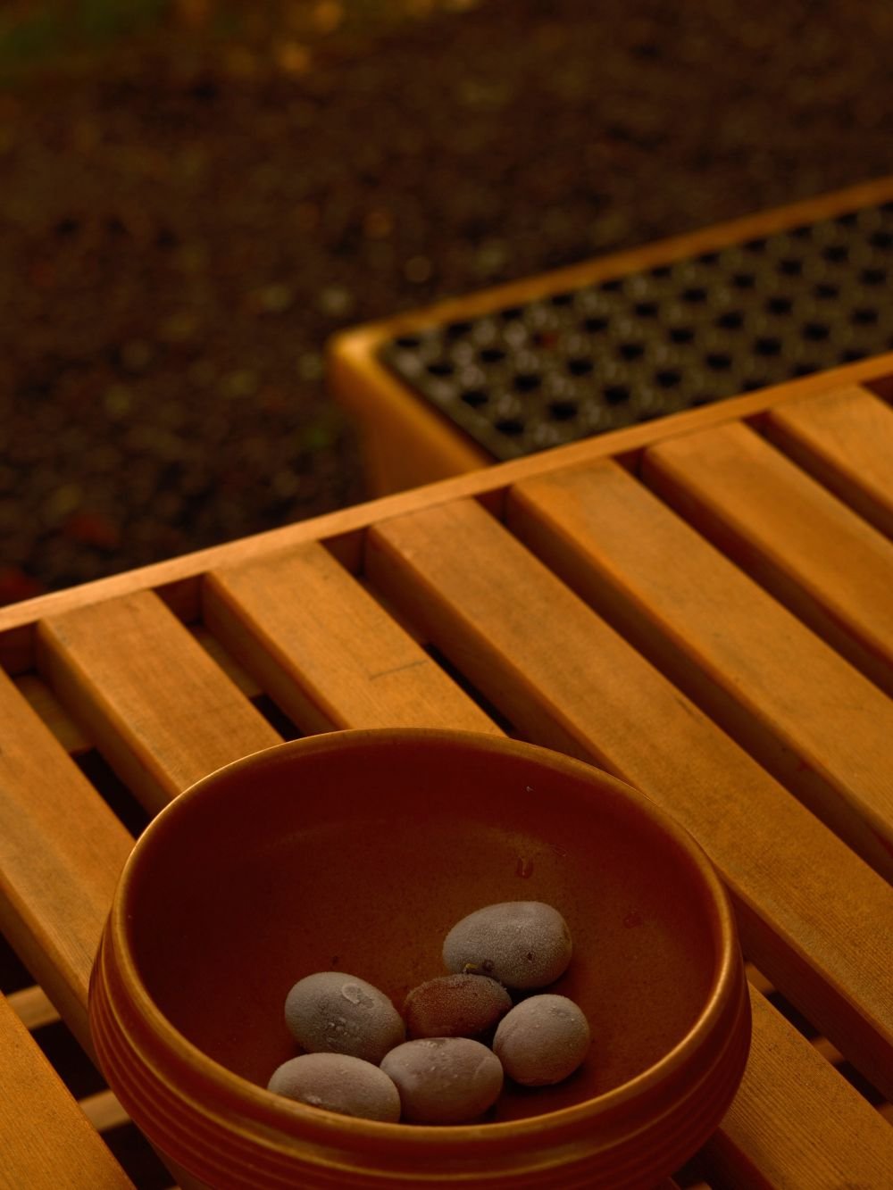 Bowl of sauna rocks on a wooden bench