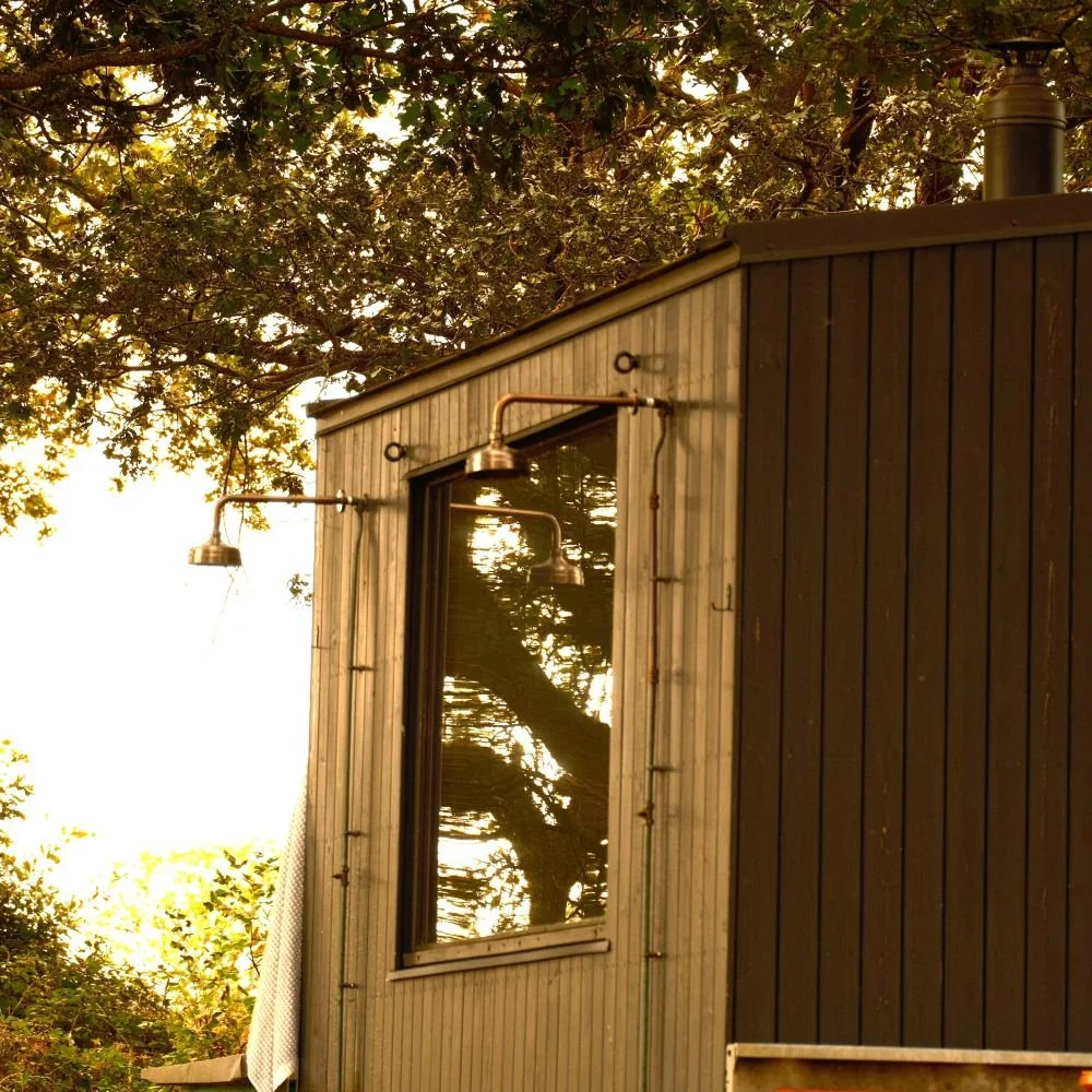 Wooden outdoor sauna hut with showers attached to exterior wall