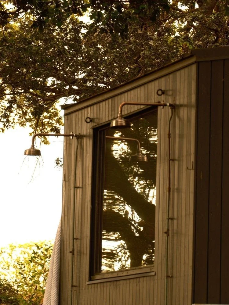 Exterior of a wooden sauna hut with showers attached to the exterior wall