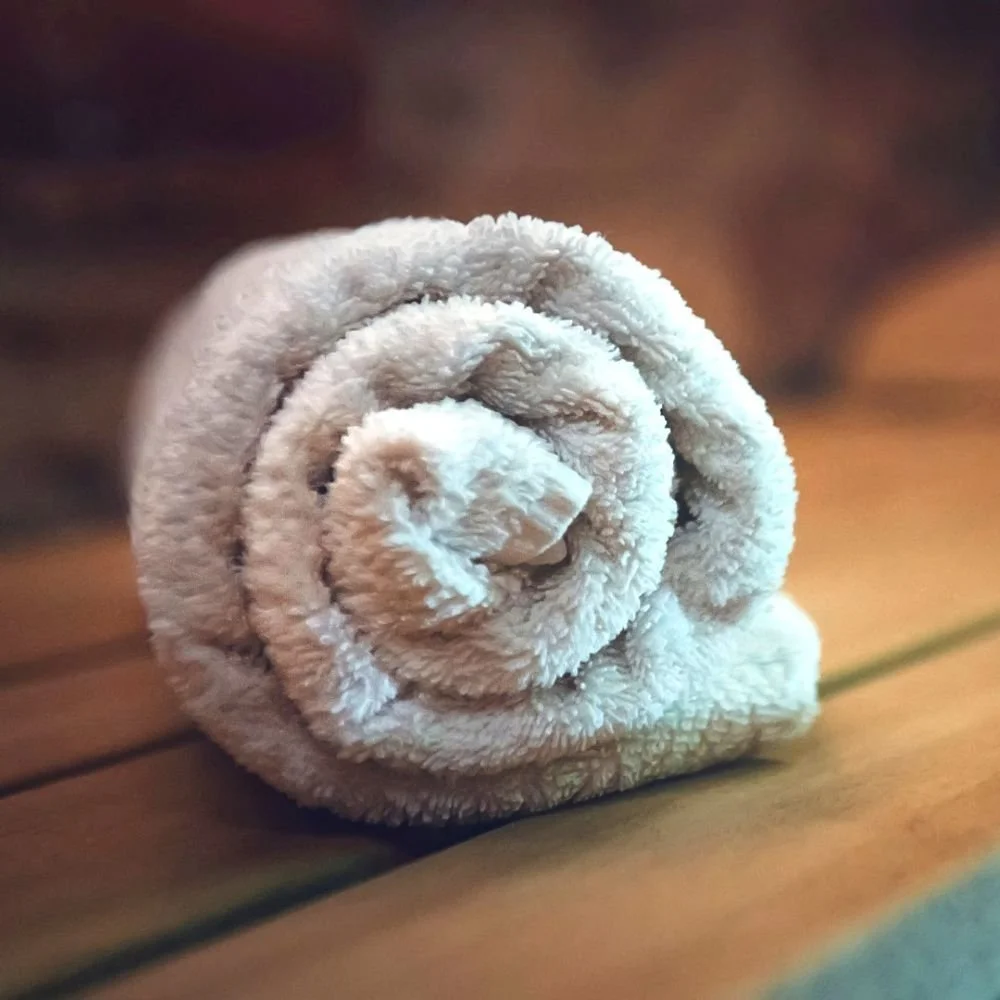 A white rolled towel on a wooden sauna bench.