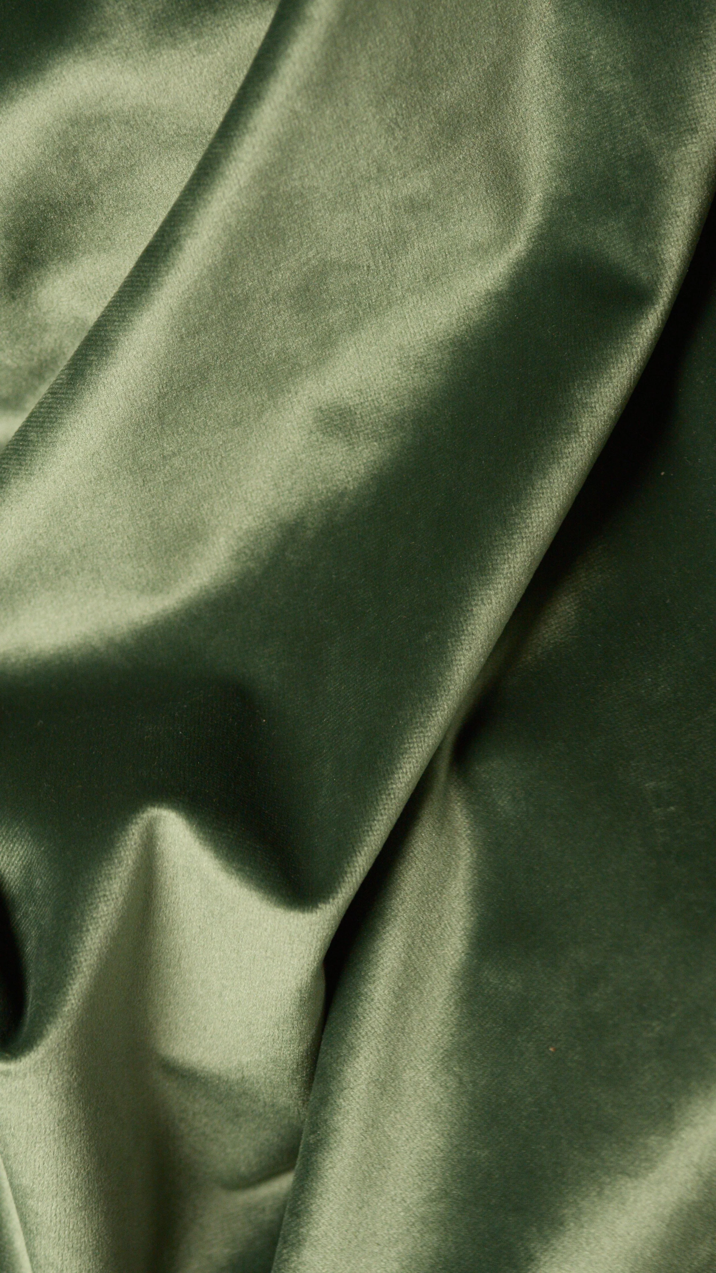Close-up of smooth, shiny, olive green satin fabric with gentle folds.