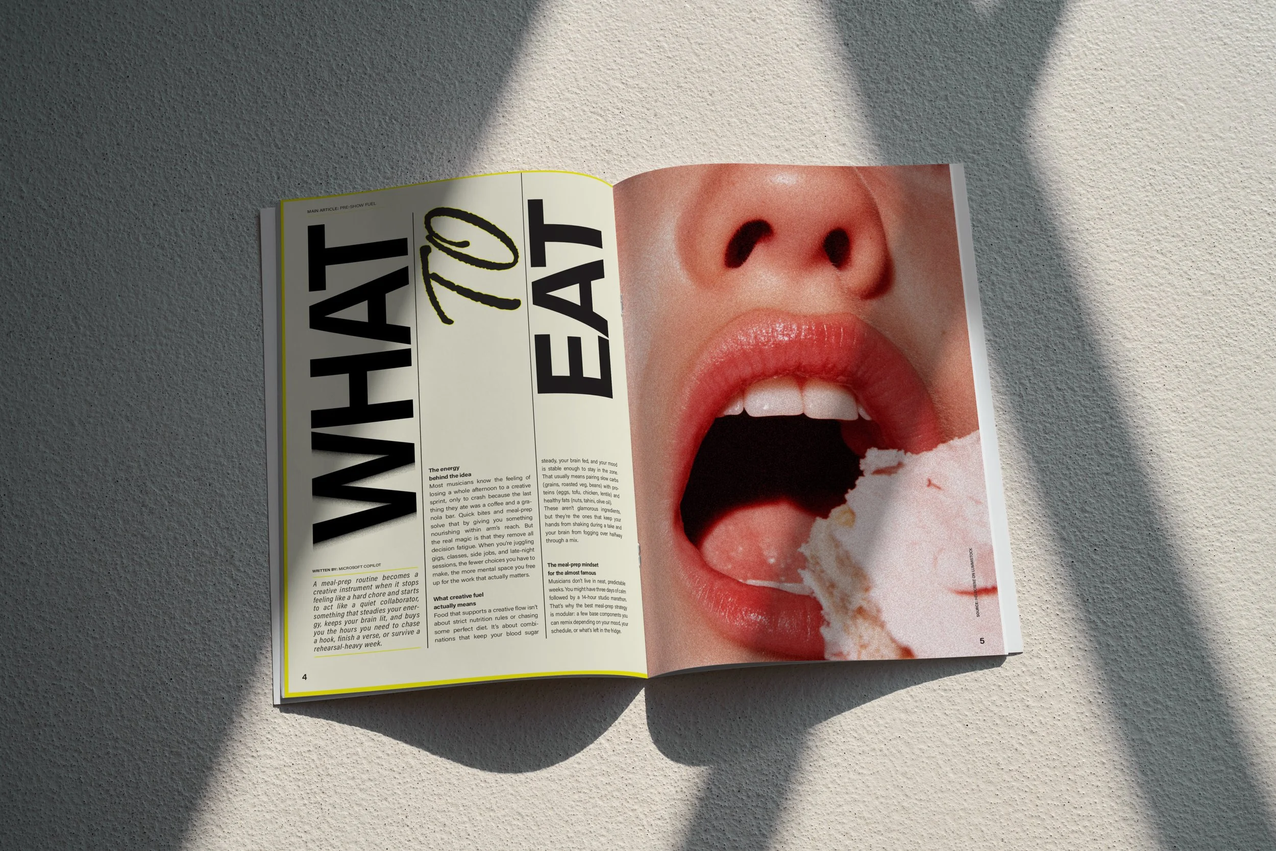 Open magazine met een grote afbeelding van een mond die een ijsje likt, op een lichte vloer met schaduw.