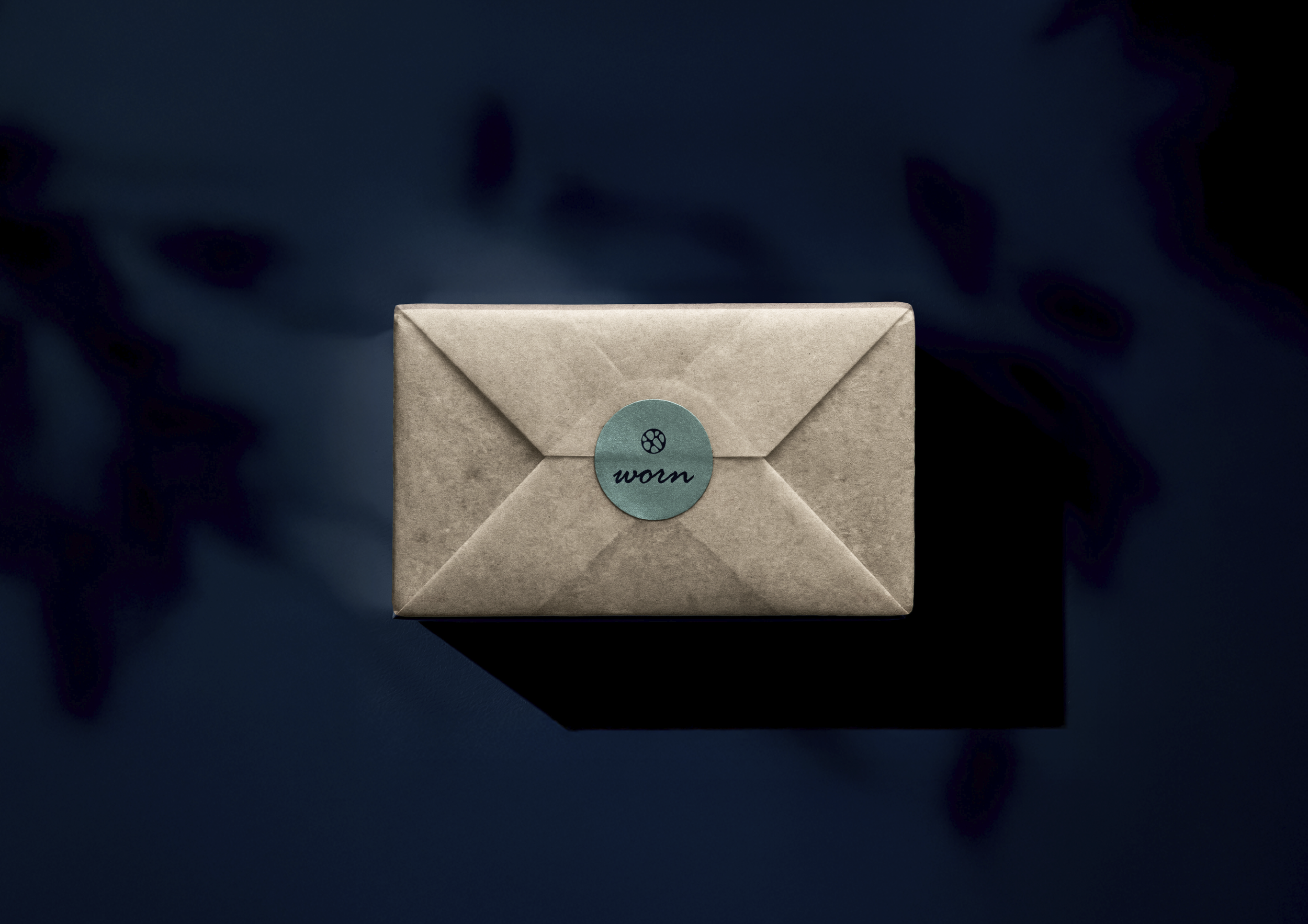Een lichtbruine envelop met een blauwwaterdicht sticker met een symbool en het woord 'worn' op een donkere achtergrond.
