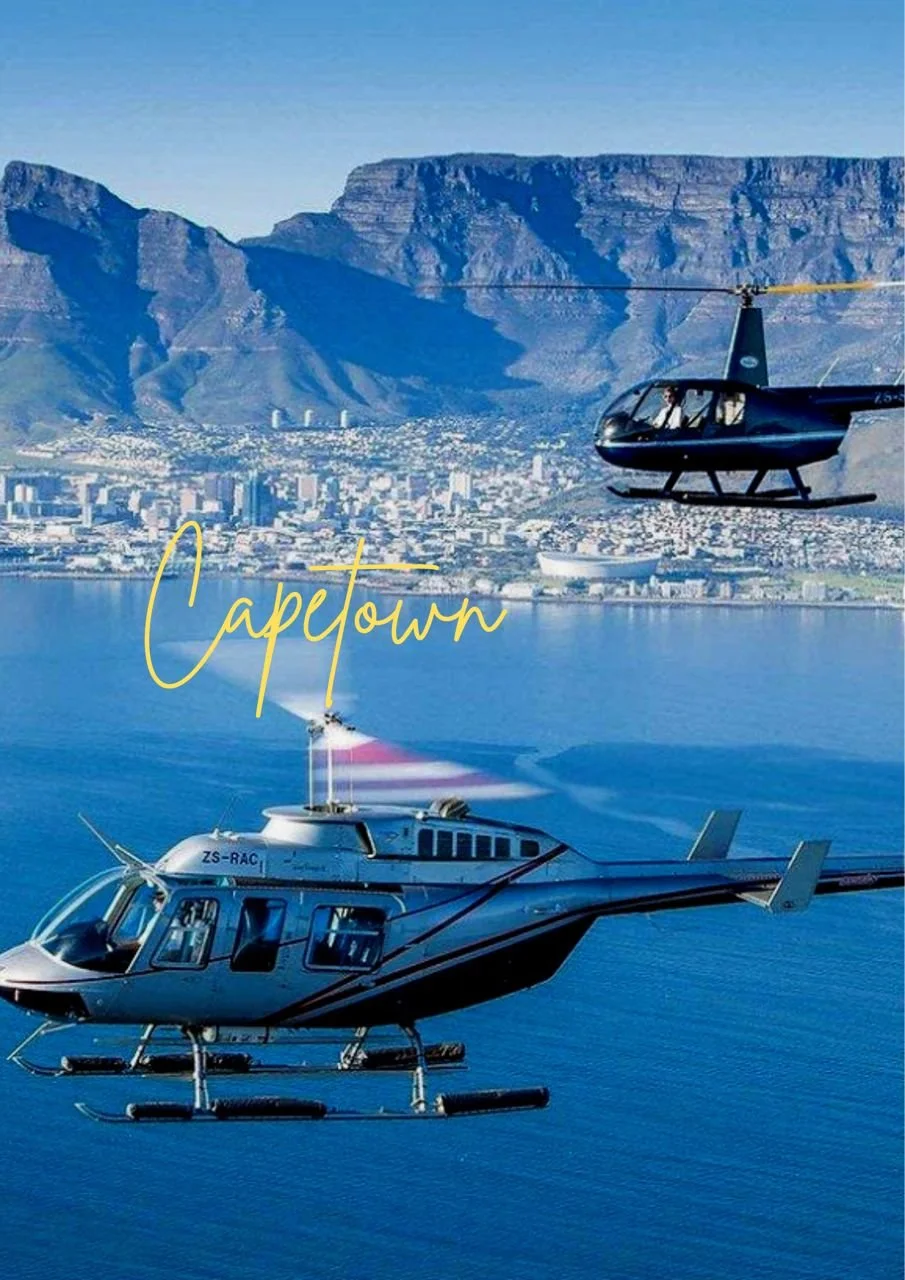 Two helicopters flying over a body of water with a city and mountains in the background, with the word 'Capetown' written in yellow script.