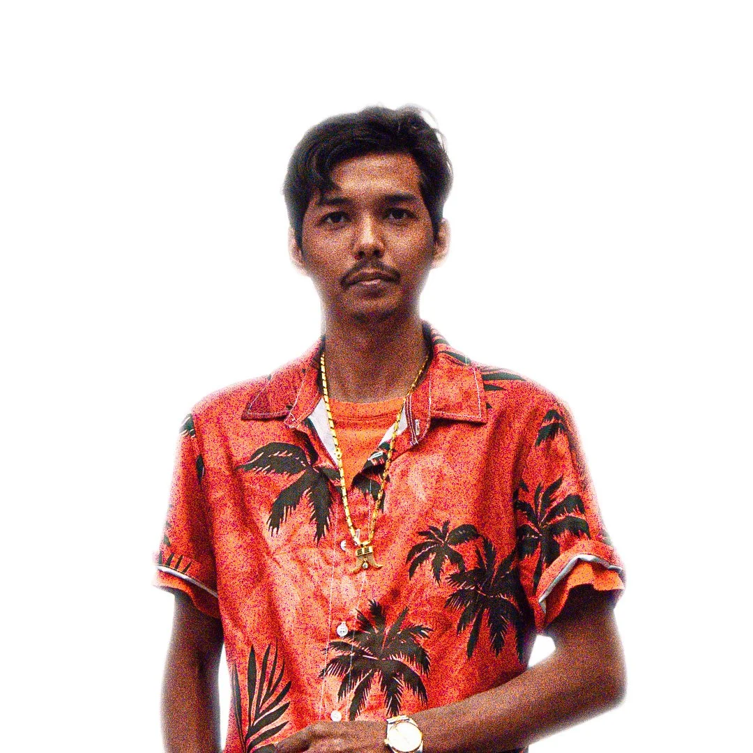Young man wearing a red Hawaiian shirt with palm tree pattern, gold chain, and wristwatch, standing against a white background.