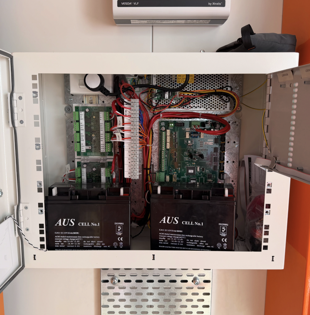 Open electrical control panel with circuit boards, wiring, and two large batteries labeled 'AUS CELL No.1' inside.
