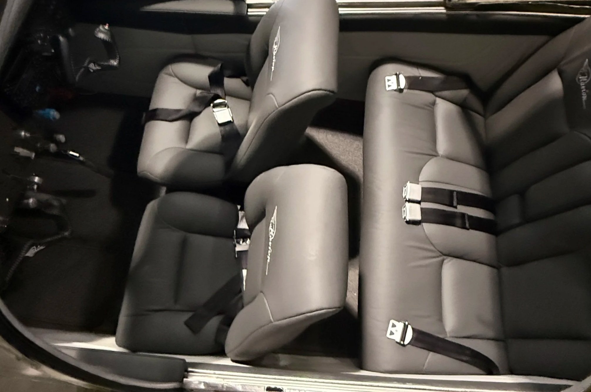 Interior of a vehicle showing multiple gray leather seats with black seat belts.