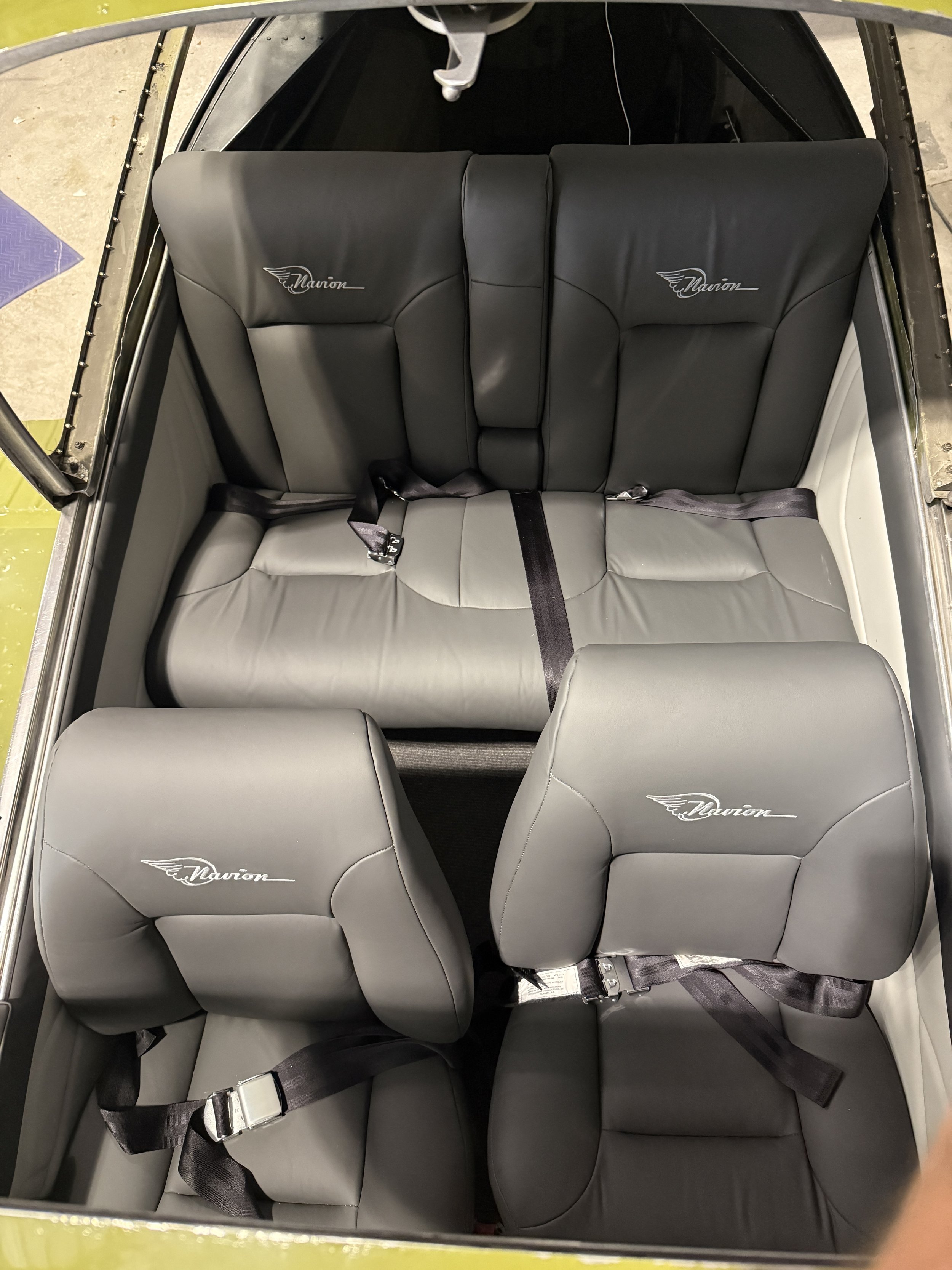Interior of a vehicle showing gray seats with the brand name 'Navion' embroidered on the headrests, and seat belts.