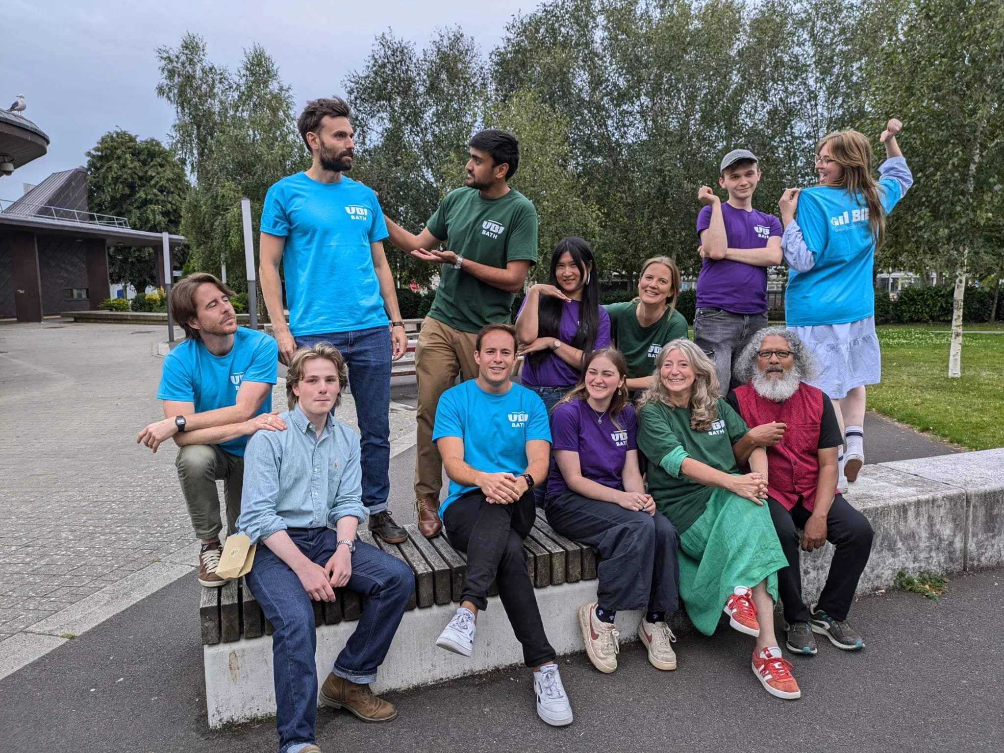 A group of volunteers and participants at the Basic Income Earth Network World Congress in Bath, wearing colourful UBI t-shirts, gathered outdoors.