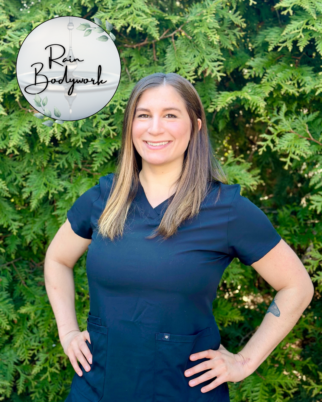 A woman with long brown hair, wearing a navy blue medical uniform, standing outdoors in front of green foliage, smiling with hands on hips, with a logo in the upper left corner that reads 'Rain Bodywork'.