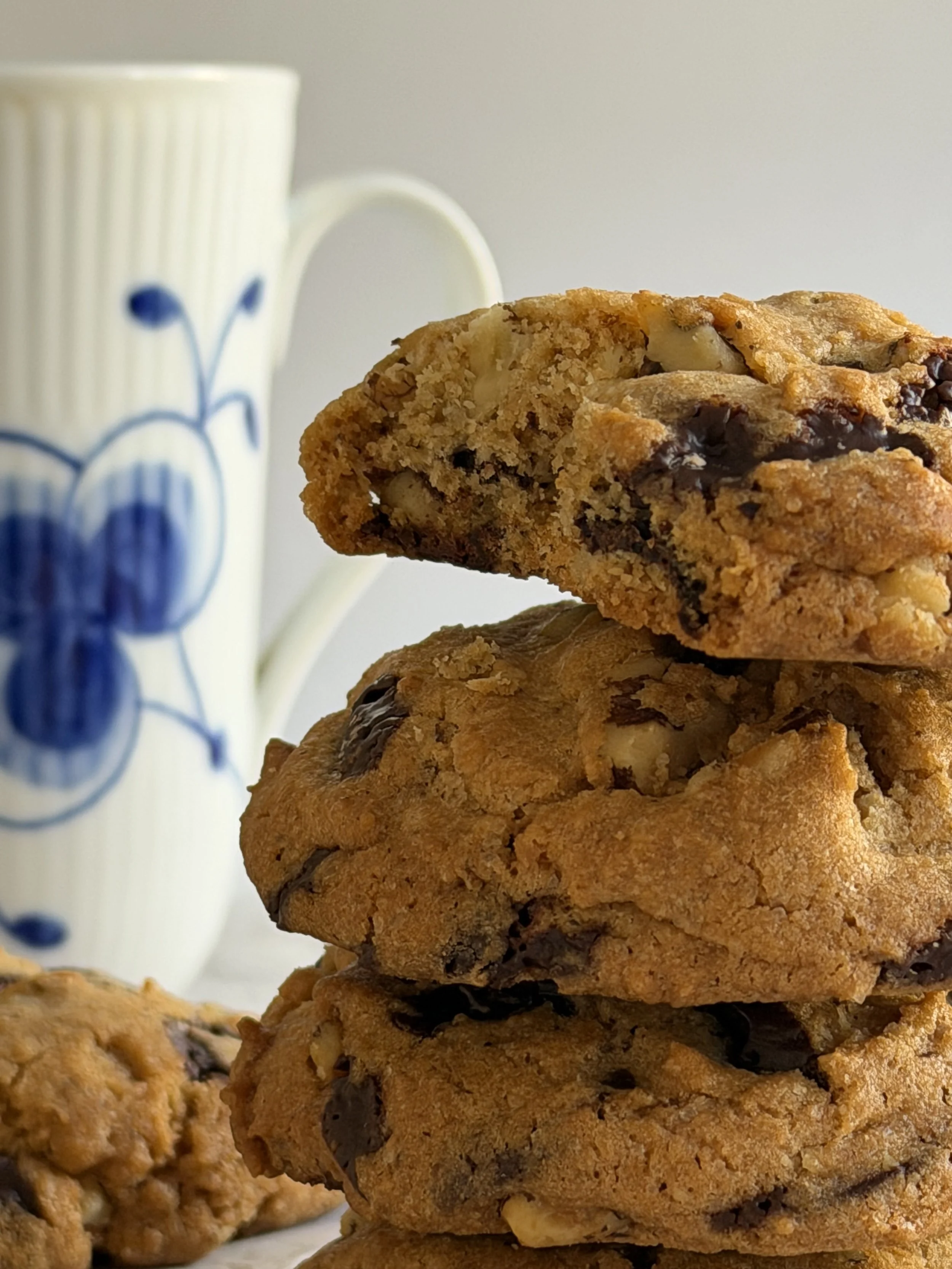 Close-up of a stack of chocolate chip cookies with a cup in the background.