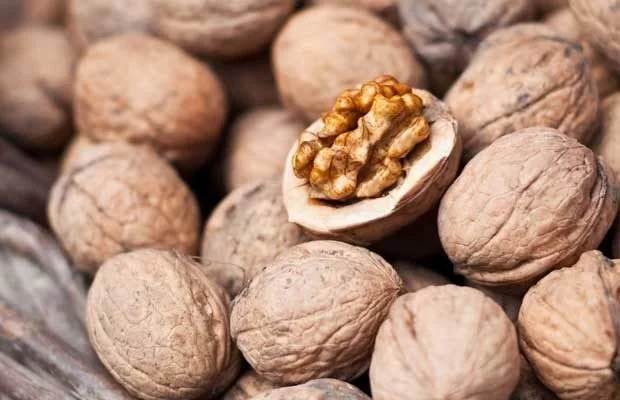 Close-up of several walnuts, one cracked open showing the nut inside.