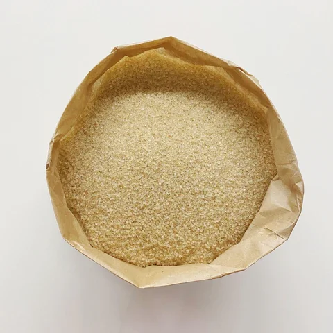 A round paper bag filled with white granulated sugar