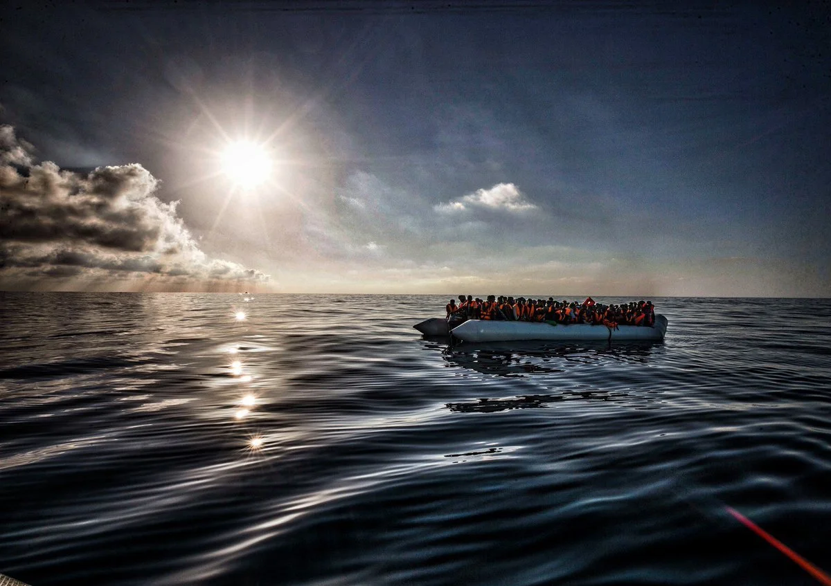 Early morning image of a raft of African migrants onboard a smuggler's inflatable rubber canvas raft in the Mediterranean. ©Robert Young Pelton. all rights reserved. 