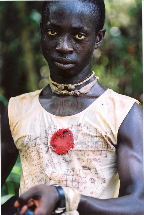 A Kamajor fighter from Sierra Leone. His shirt is covered in Arabic verses from the Koran, and he insists his amulets and shea butter anointment protect him from bullets. ©RYP, all rights reserved