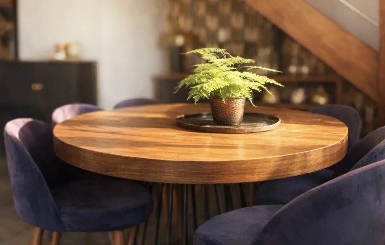 Table ronde en bois avec une plante verte en pot au centre, entourée de six chaises en velours bleu foncé.