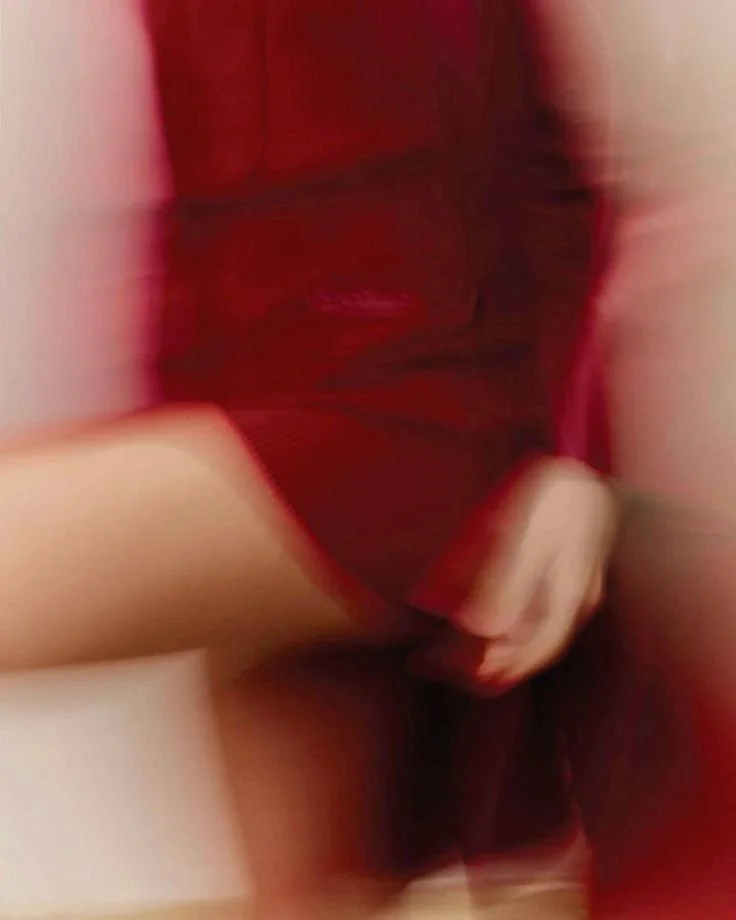 A person wearing a red dress holding a bag, with part of their arm visible.