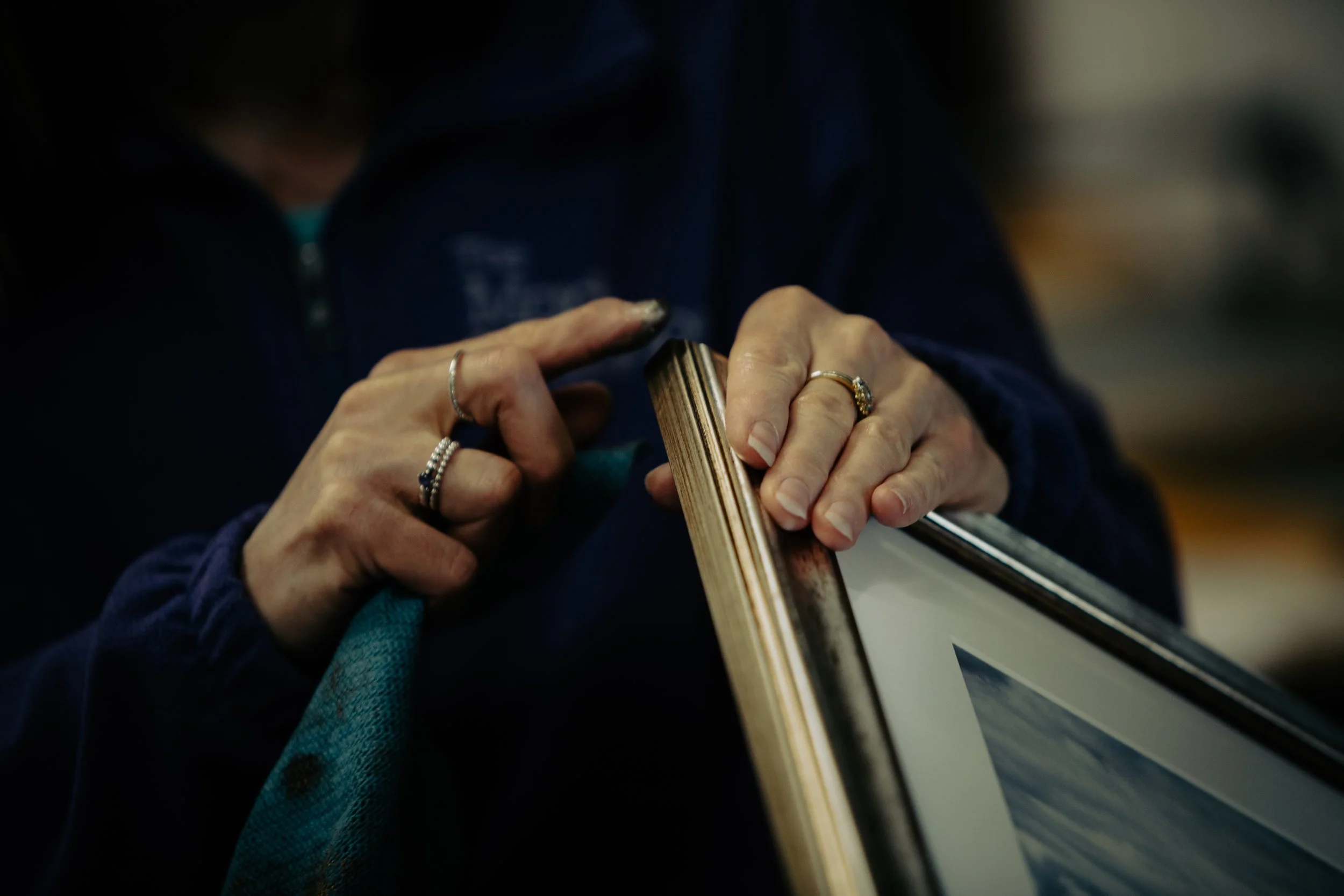 Close-up of a person applying finish to a newly framed piece of art.