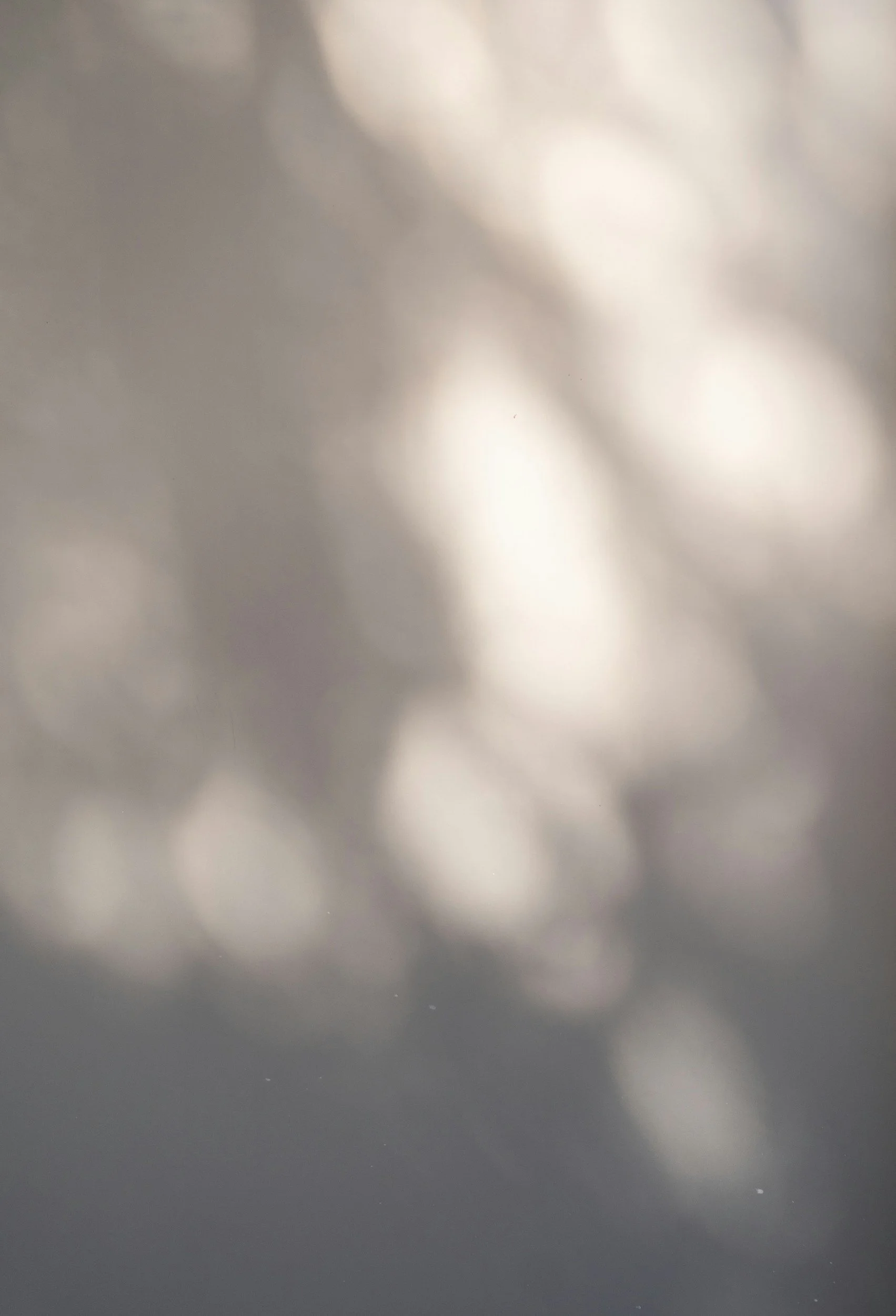 Blurred metallic surface with shiny, reflective areas and small white spots.