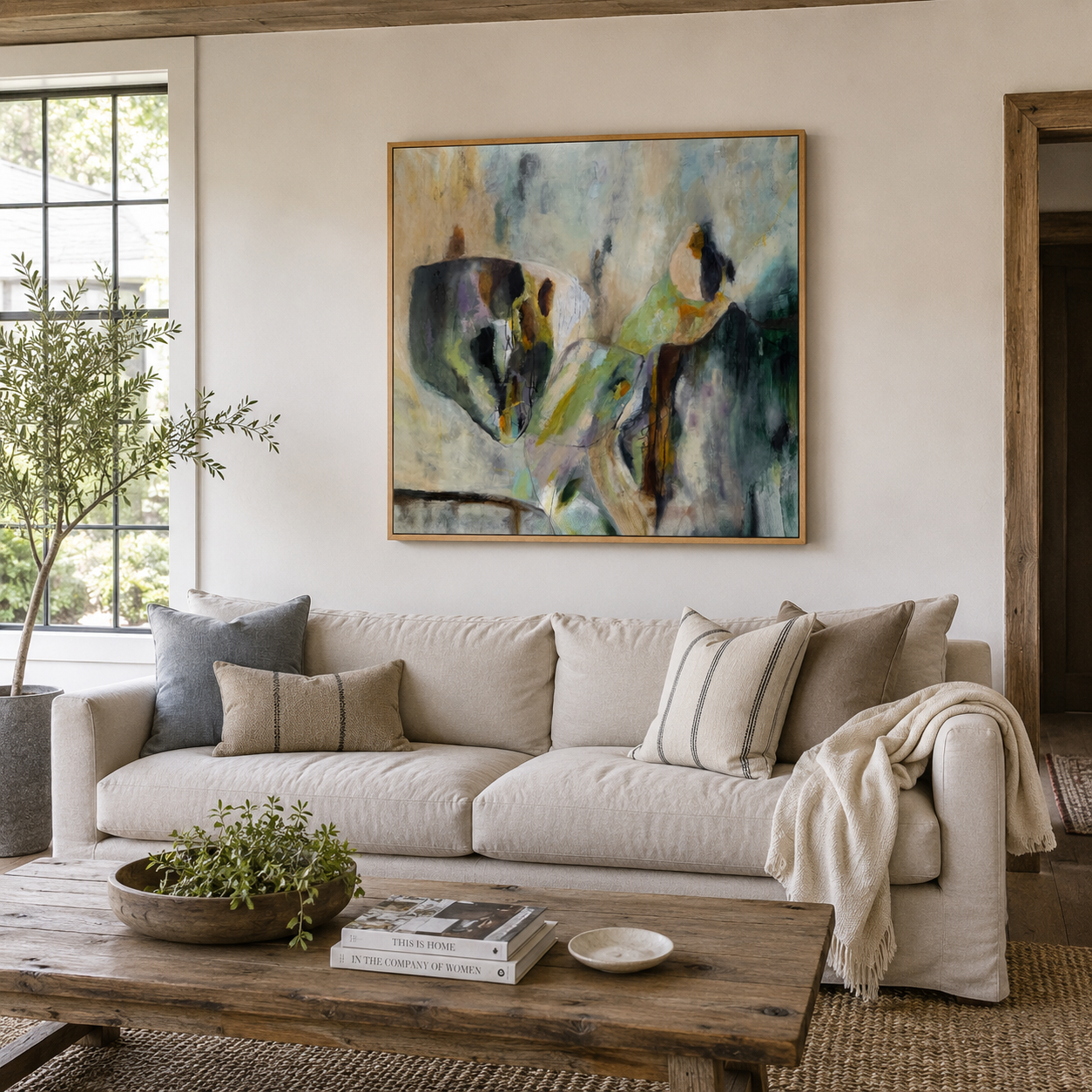 Living room with a beige sofa, decorative pillows, a wooden coffee table with a large abstract painting by Brita Nordin on the wall