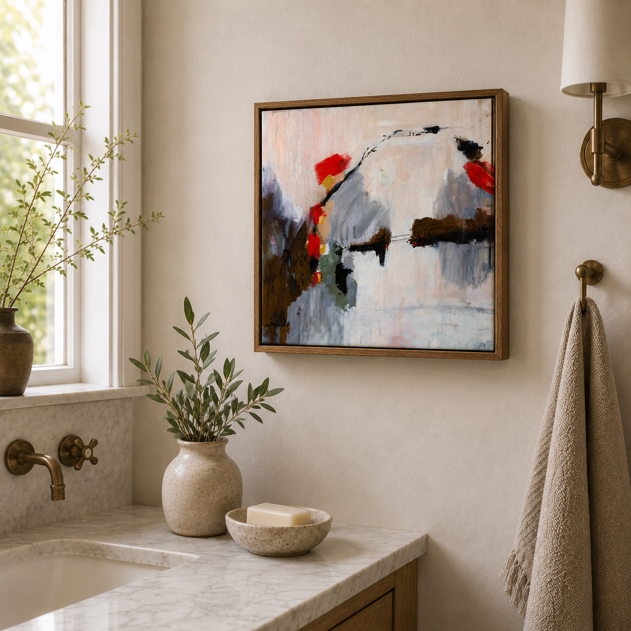 Interior view of a bathroom with an abstract oil painting by Brita Nordin on the wall, a window with a plant on the ledge, a beige towel hanging on a brass hook, and a marble sink.