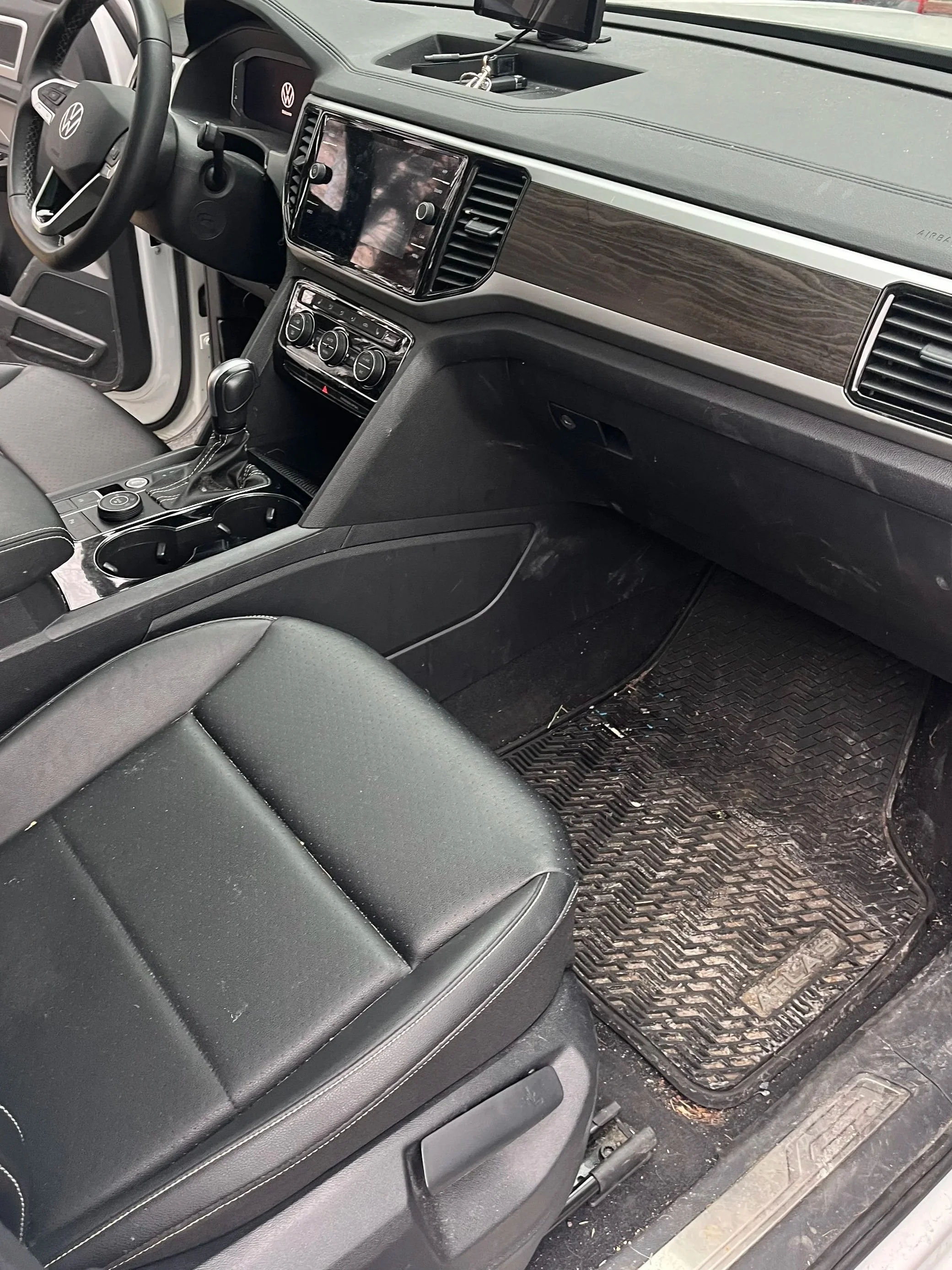 The interior of a Volkswagen vehicle showing the front passenger seat, dashboard, center console, and floor mats.