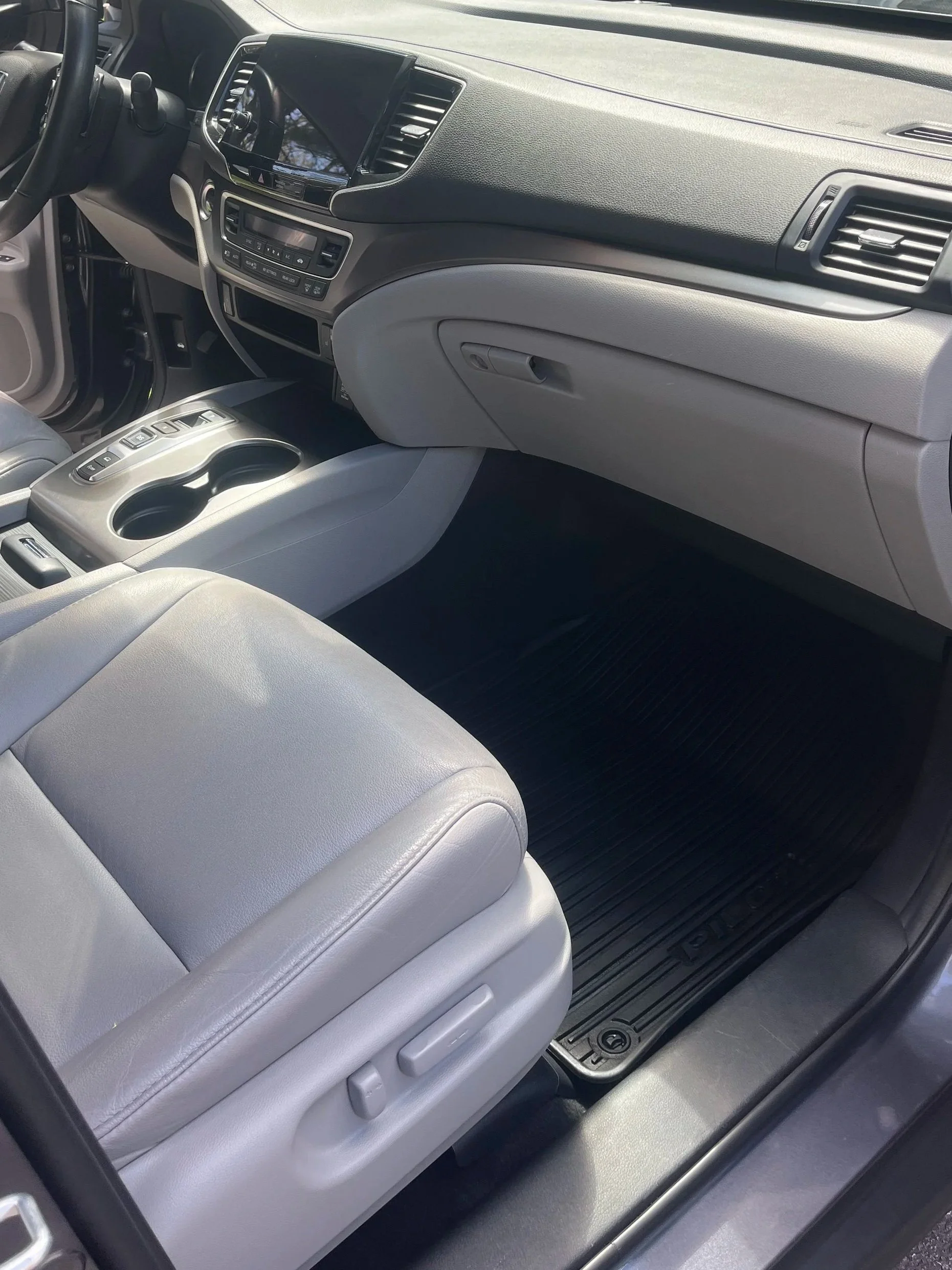 Inside of a vehicle showing the front passenger seat, dashboard, and center console with cup holders.