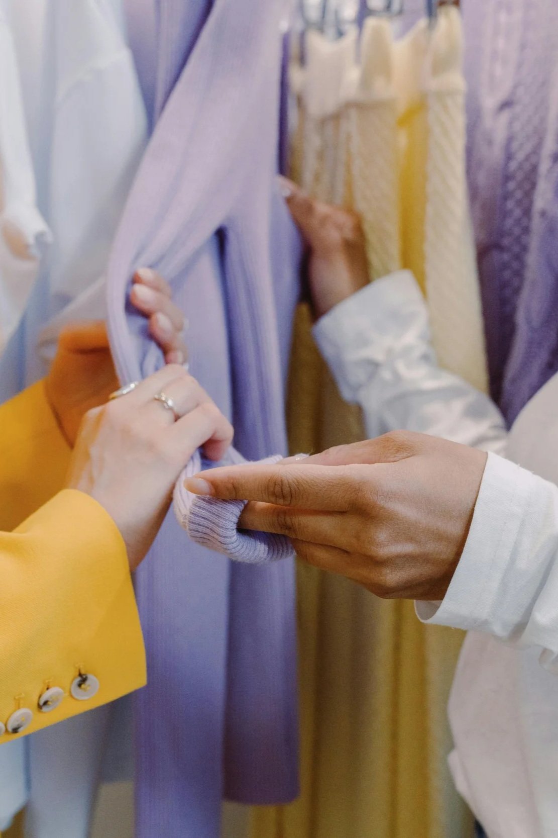 Two women looking at an item of clothing in a shop and feeling the fabric