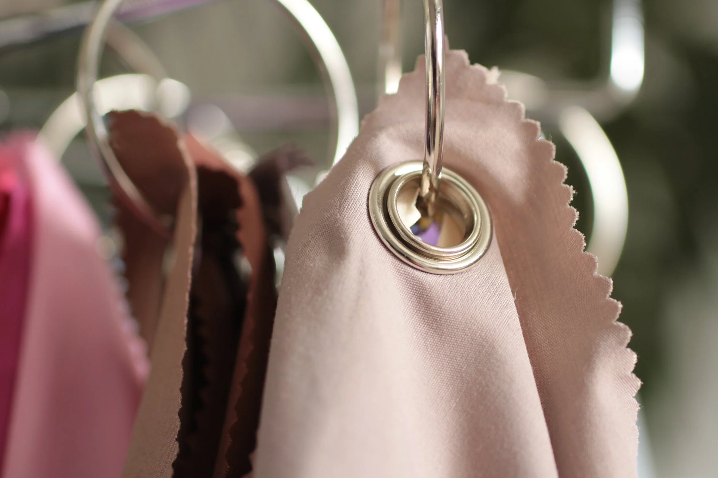 A close up photo of a light pink drape hanging on a hook