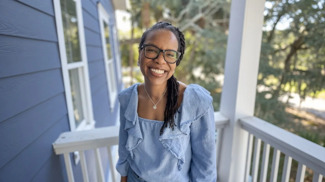 Tamara Grossett in a blue dress, smiling on a porch.