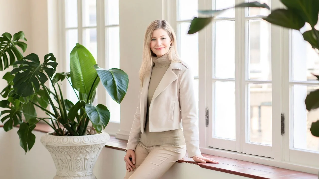 Tiffany Jeffers resting on a window ledge in neutral clothing.