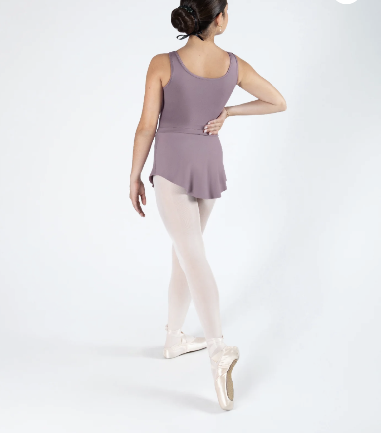 A woman in a purple ballet top, beige tights, and ballet shoes standing with her back to the camera, in a ballet pose.