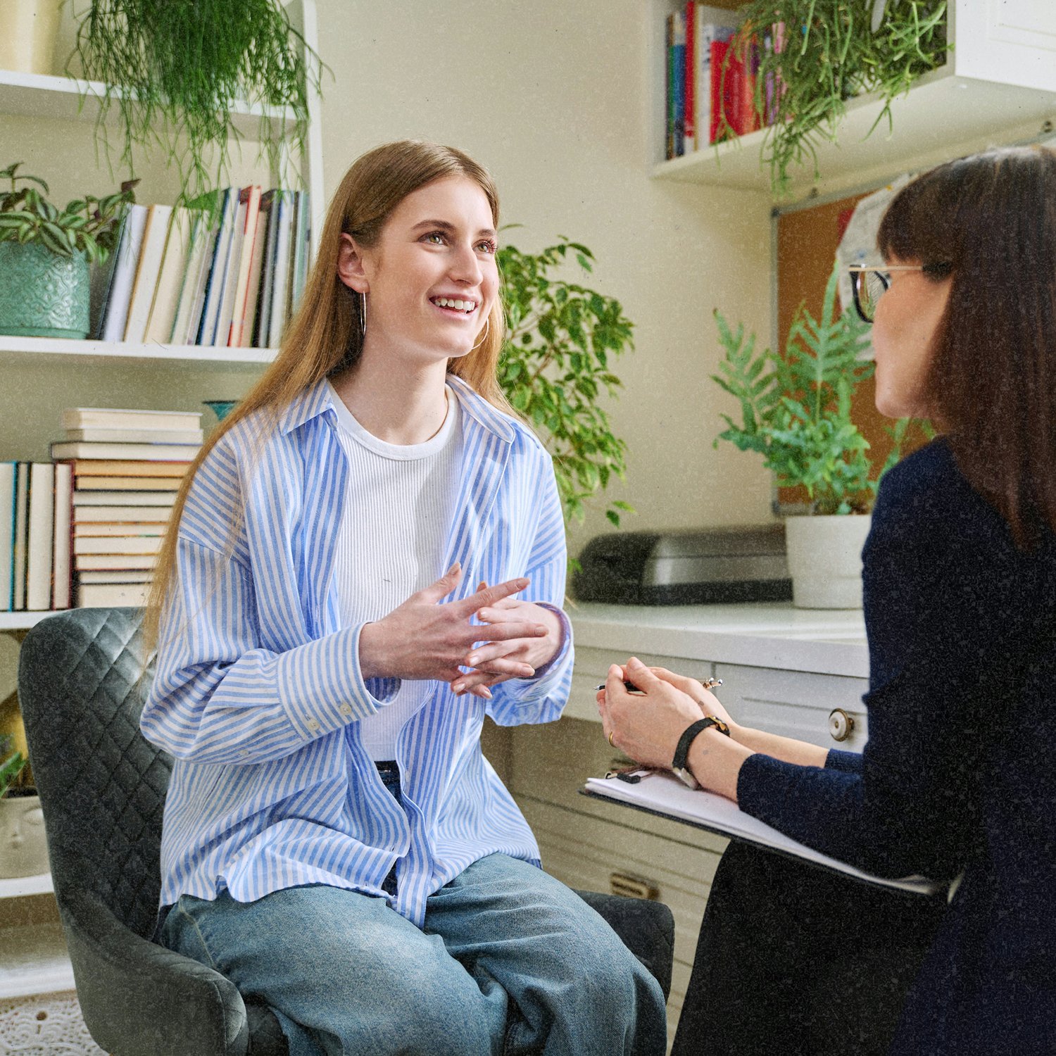 A young woman is sitting and smiling during what appears to be a therapy session at school.
