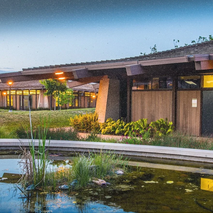 Exterior view of a Foothill College with a water feature and landscaped garden at dusk.