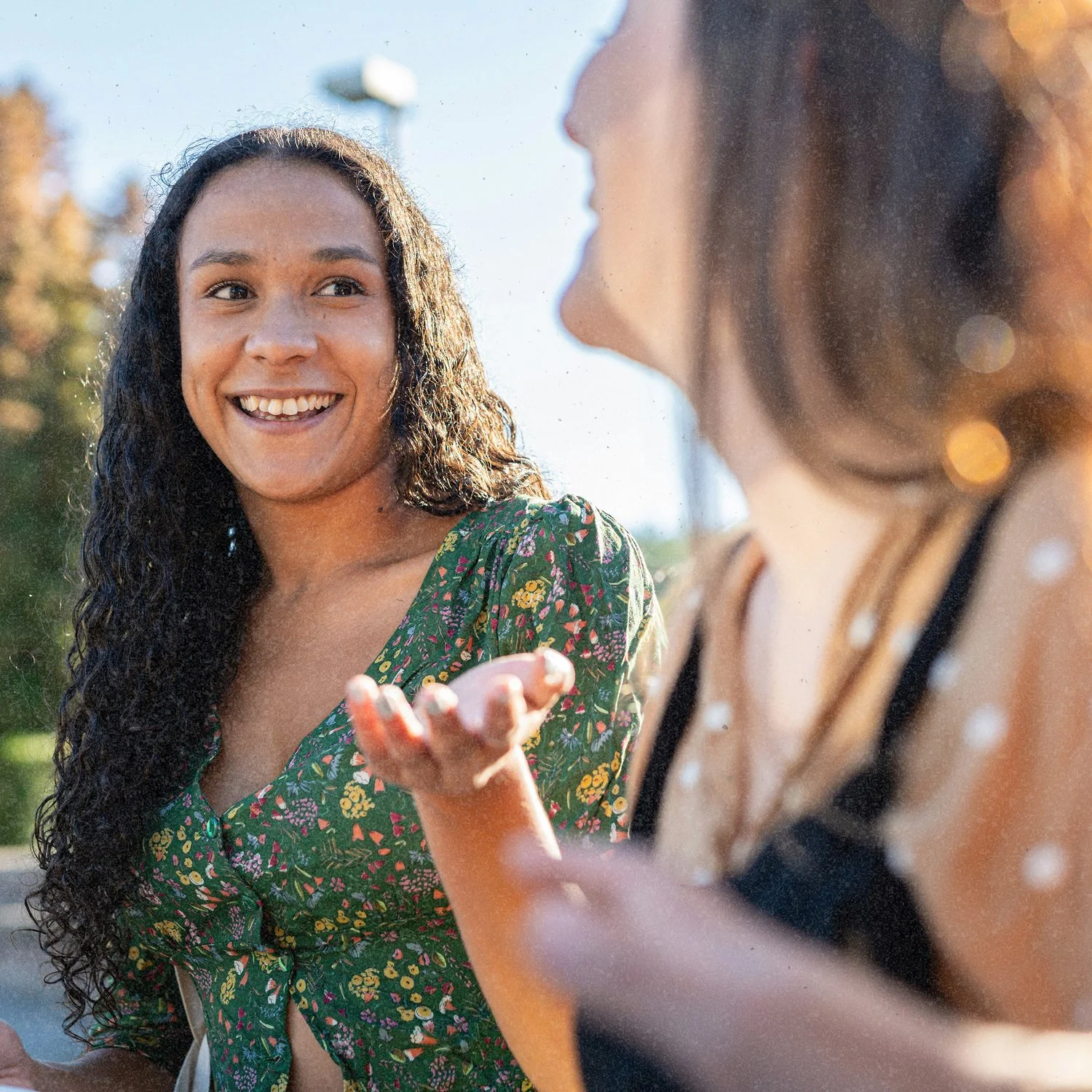 Two women having a lively conversation outdoors on a sunny day