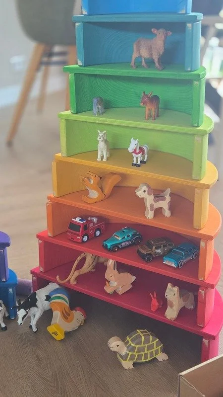 Een kleurrijke stapel houten schijven en bogen / speelgoedblokken met kleine dieren en autootjes erop. creatief gebouwd met loose parts, open eind speelgoed