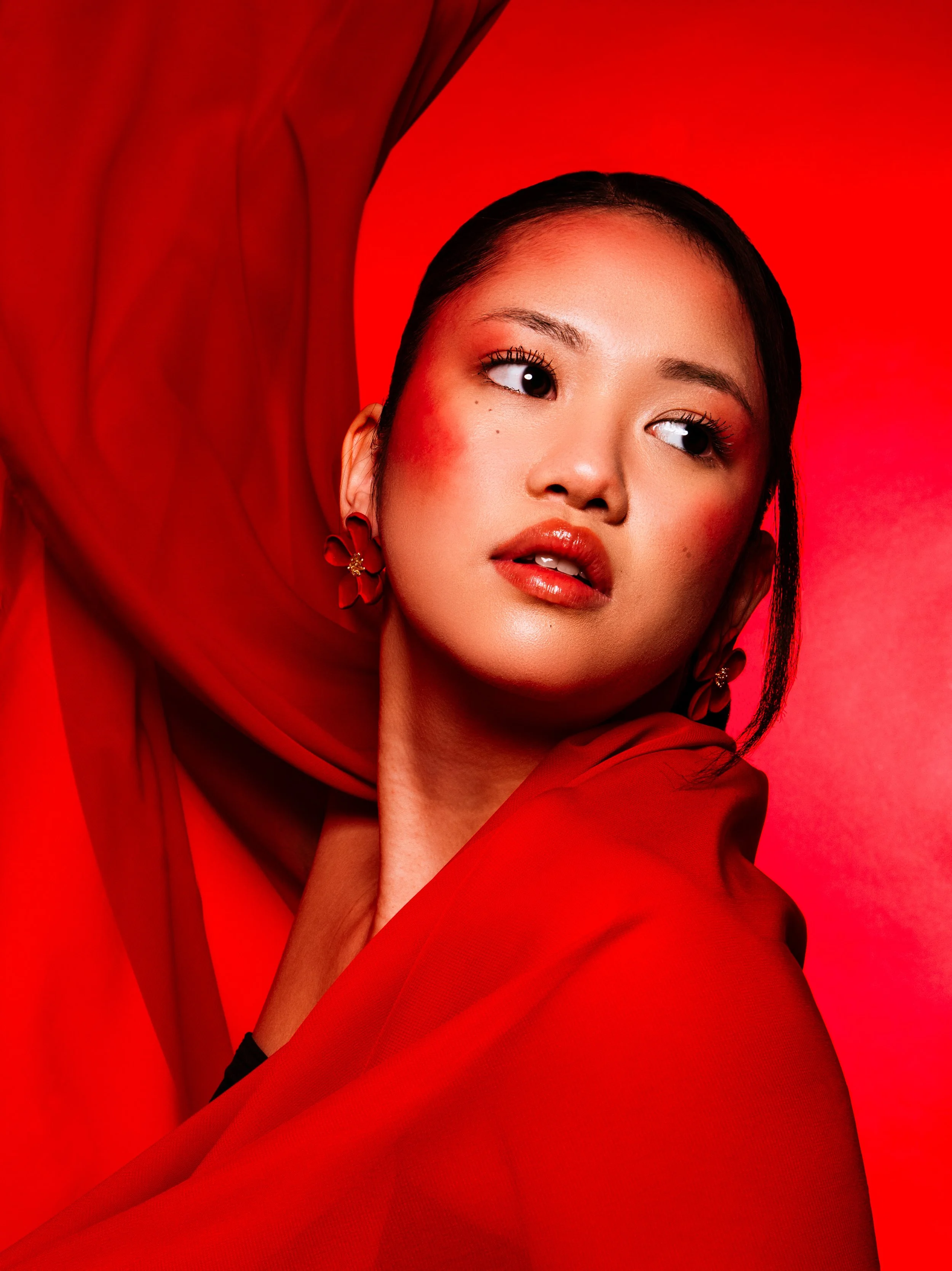 Portrait d'une femme asiatique avec un maquillage maquillage naturel, portant une robe rouge, avec un fond rouge