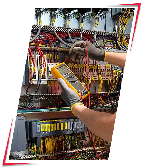 Technician testing electrical wiring with a multimeter in an electrical control panel.