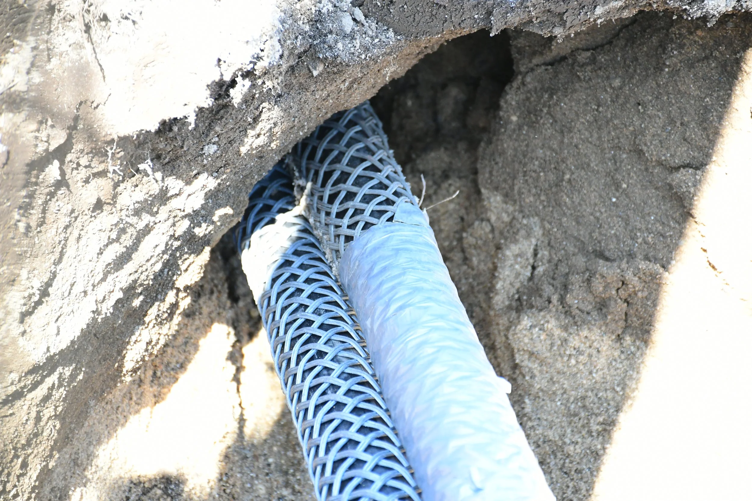 Two conduits being pulled through bored hole
