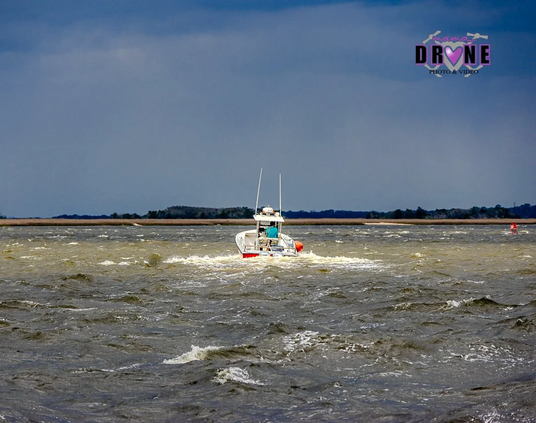 Boat on rough open water with land in the far background.