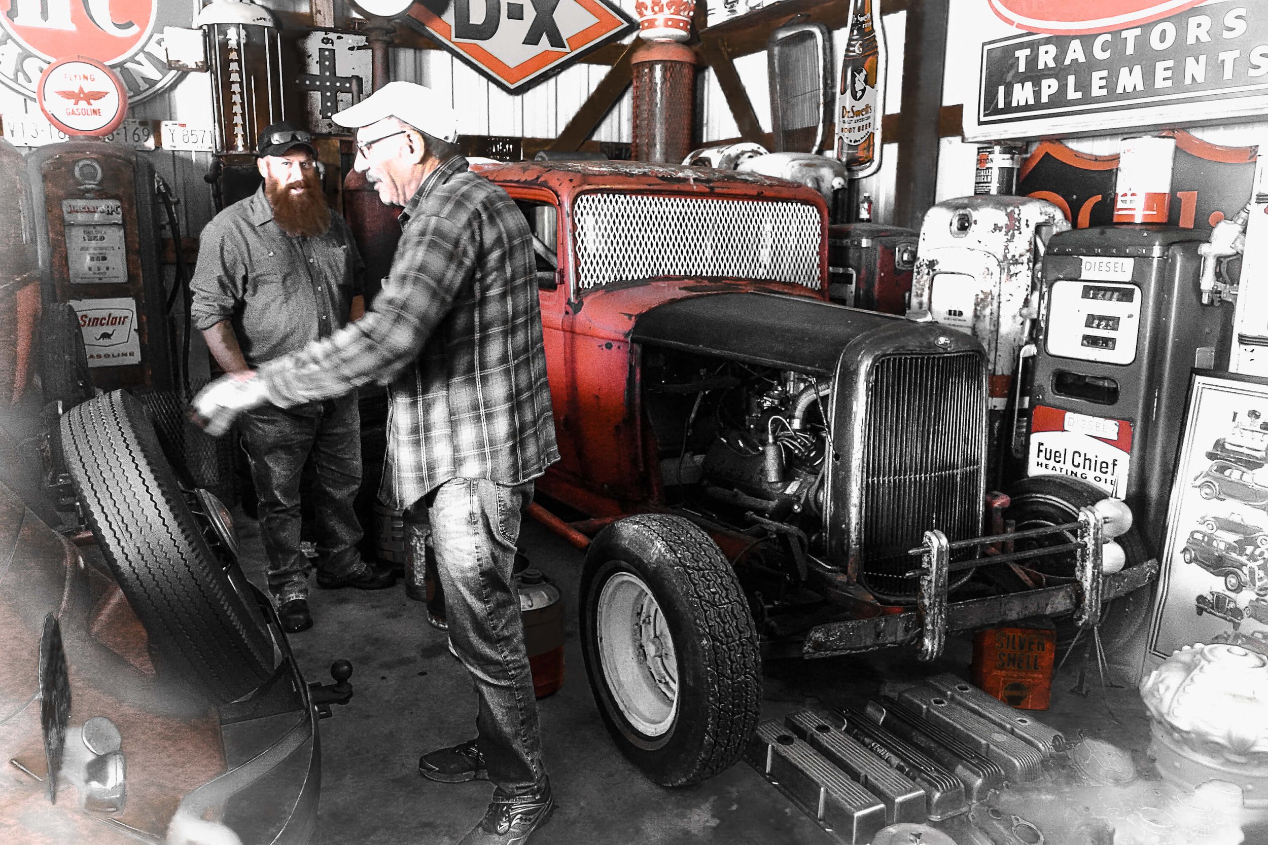2 men in garage next to vintage car.