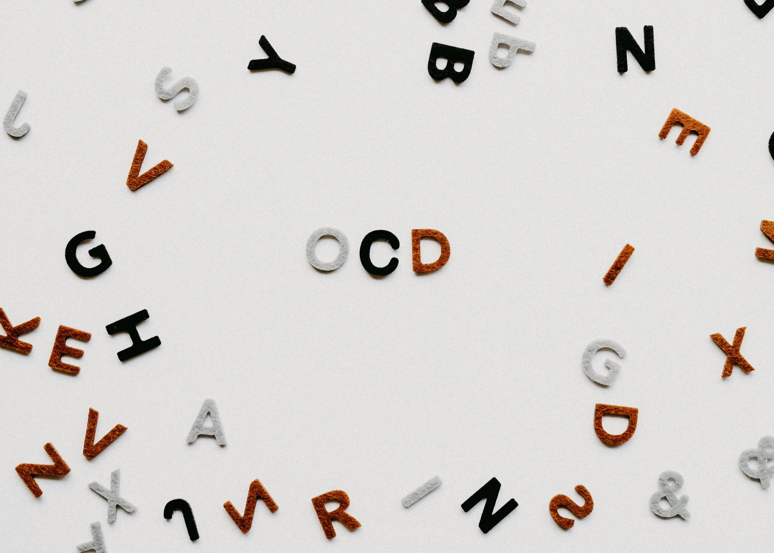 Scattered letters symbolizing racing thoughts, OCD, and the challenge of practicing self-care