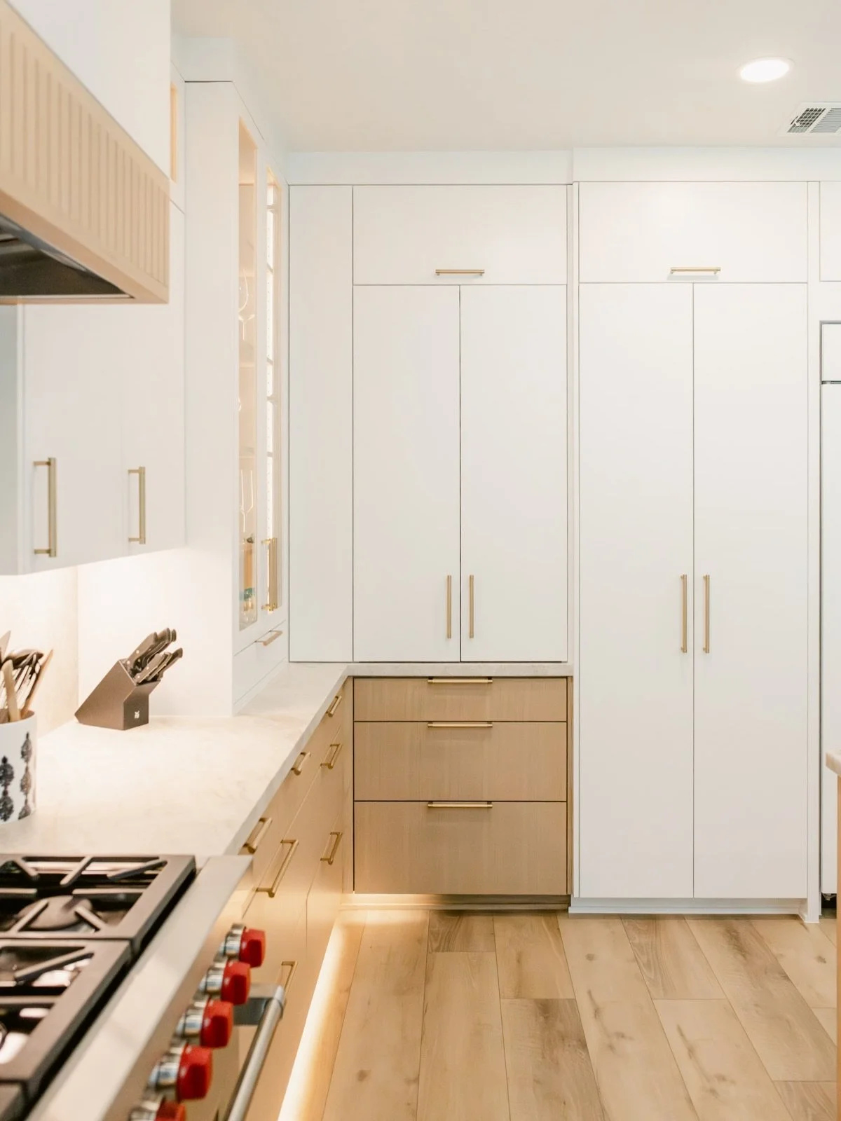 This wall of cabinets is hiding more than you&rsquo;d think.

Behind these doors: an appliance garage with the microwave, toaster, coffee maker, and mugs, plus a pull out pantry with sliding drawers for snacks and pantry basics. Closed, it all reads 