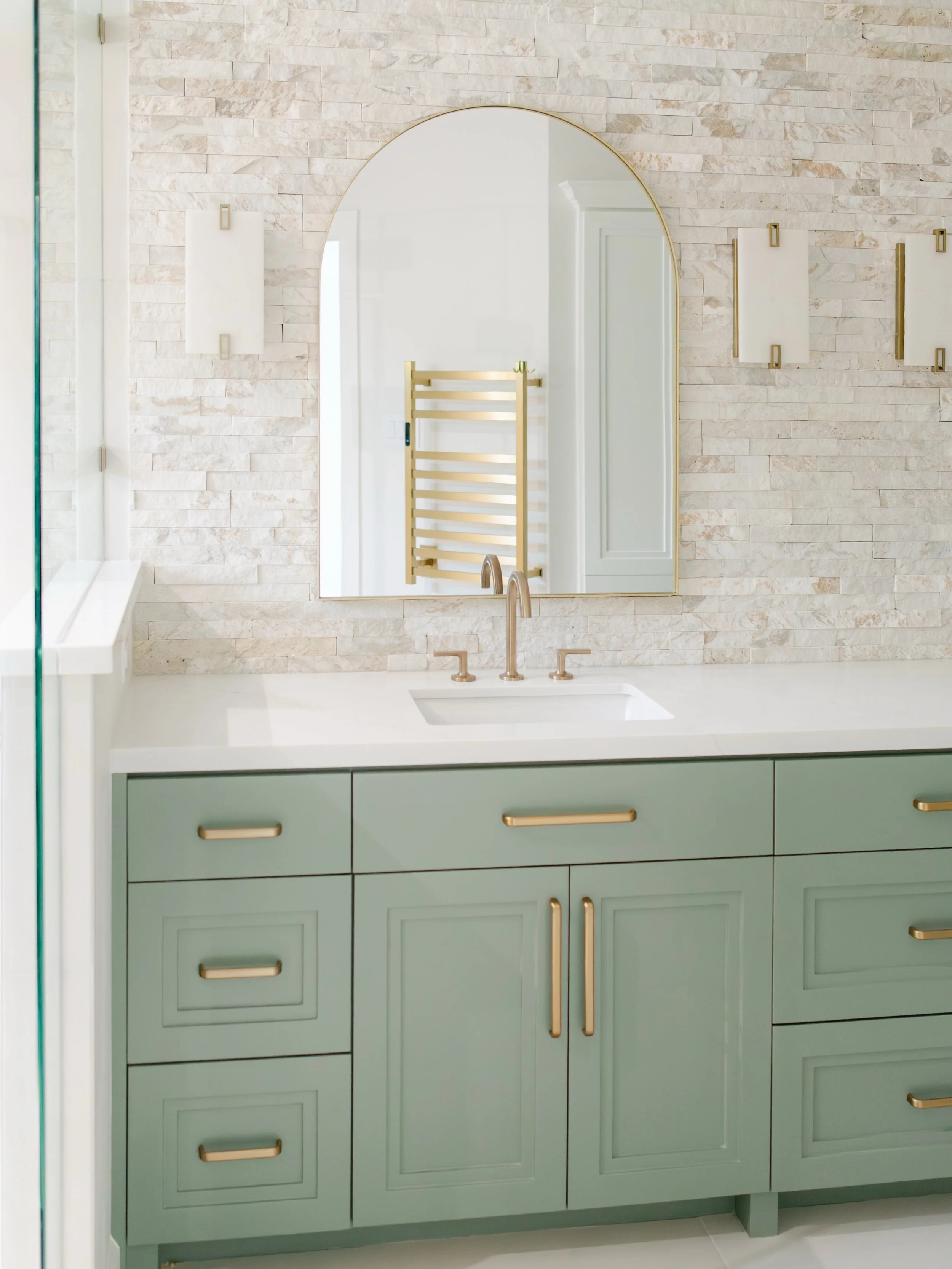 Pretty on the outside, a little bit futuristic underneath. 

A seafoam vanity, stacked stone, and brass details up top. Behind the scenes, a smart shower valve to set your exact temperature and a Toto smart toilet. Swipe to see the shower in action.
